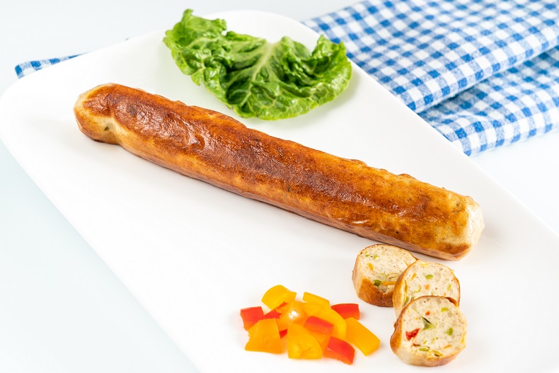 Damhus Veggie-Chili-Cheese-Griller, 5x60g, zarte Eigenhaut Eine vegetarische Bratwurst auf einem Teller mit etwas Gemüse. Im Anschnitt der Wurst ist auch Gemüse erkennbar.
